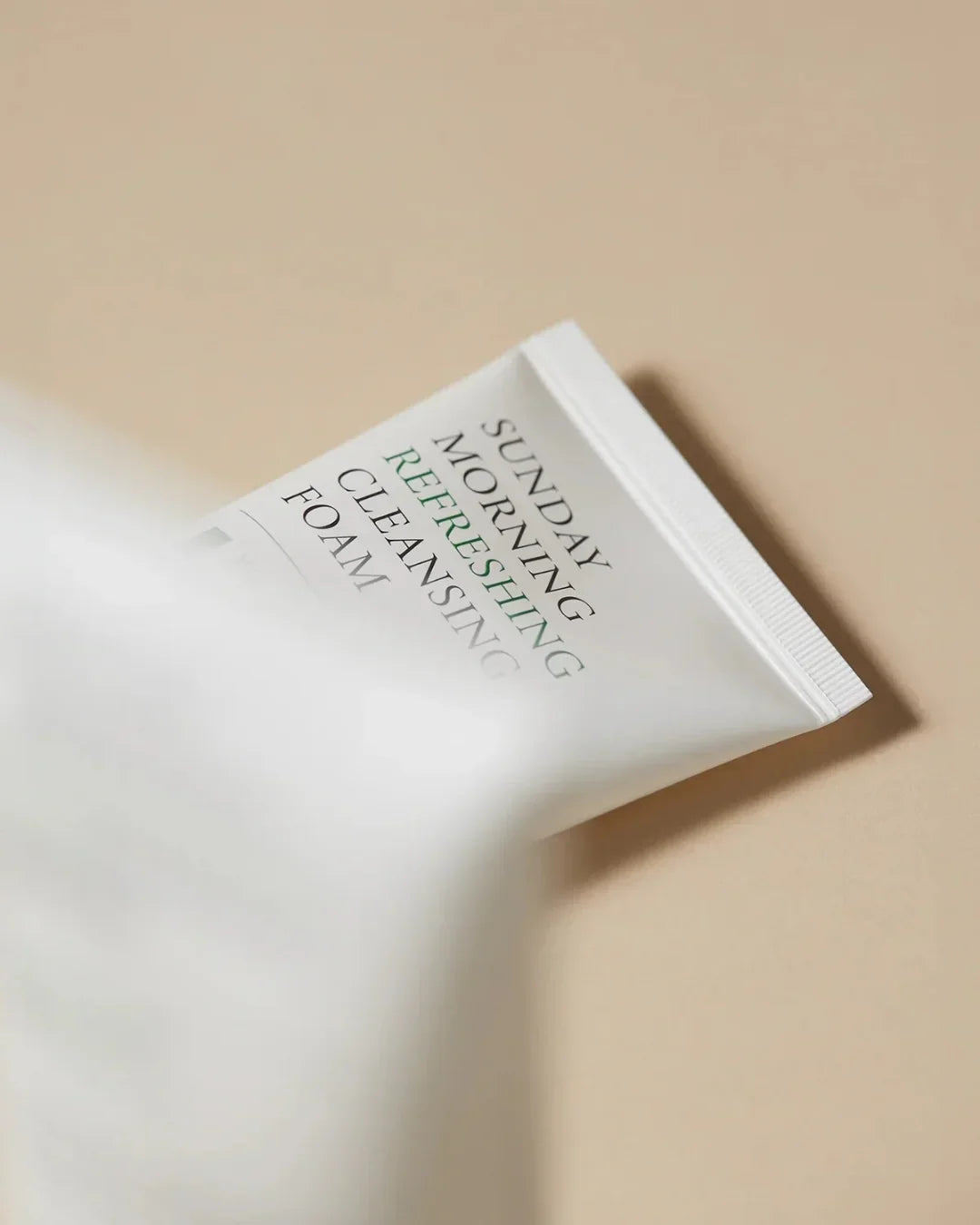 White tube of Sunday Morning Refreshing Cleansing Foam on beige background skincare product