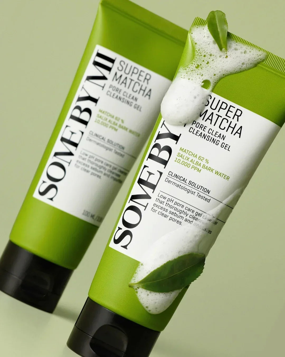 Two green tubes of SOME BY MI Super Matcha Pore Clean Cleansing Gel with foam and green leaves on a light green background