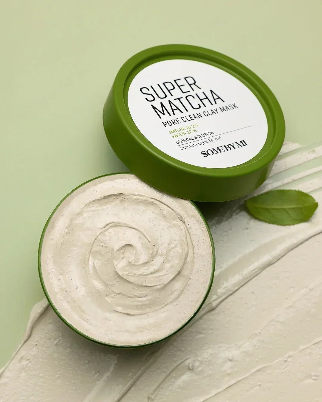 Open container of Some By Mi Super Matcha Pore Clean Clay Mask with green lid and smooth clay texture on green background
