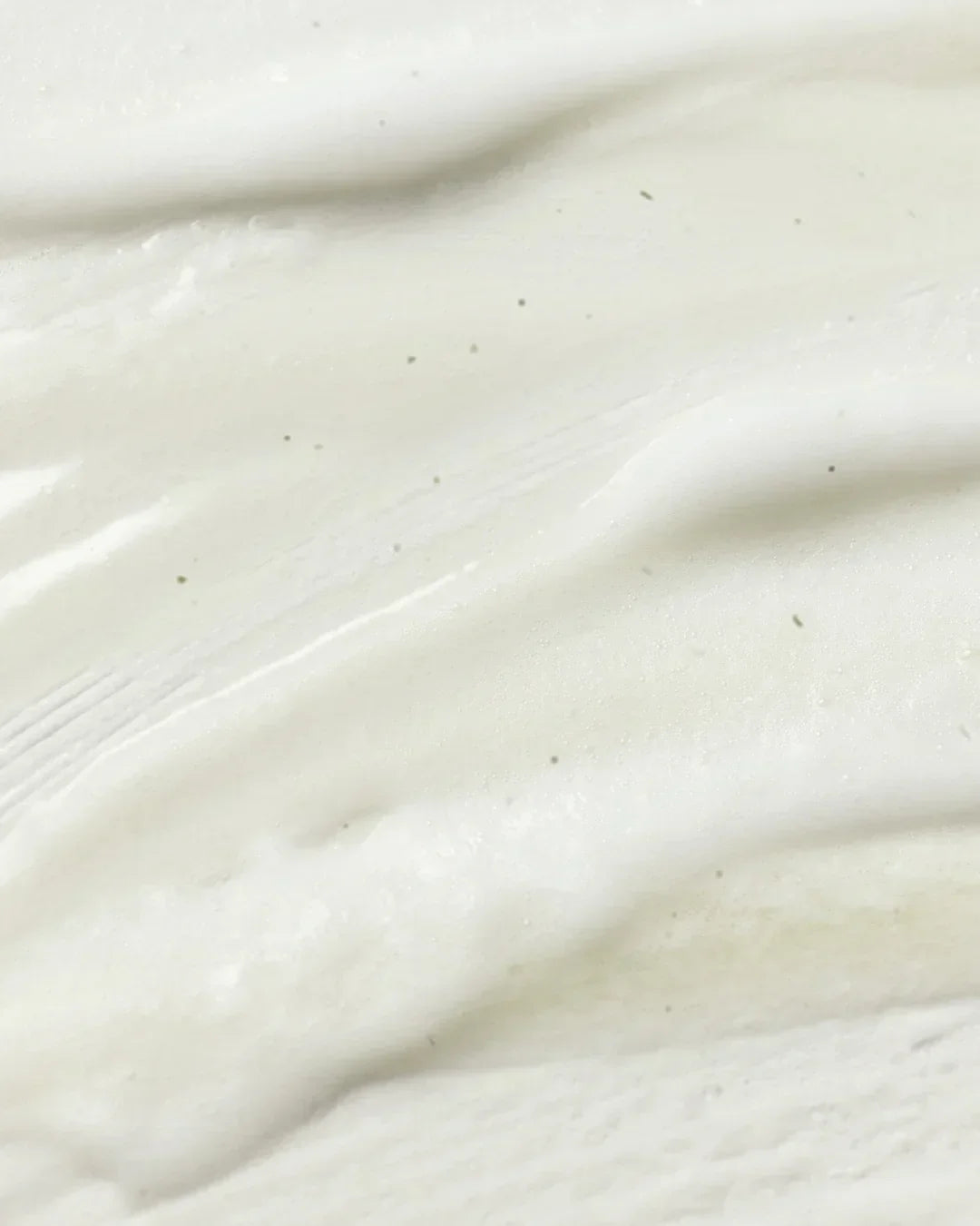 Close-up of smooth creamy white cleansing gel texture with tiny dark specks