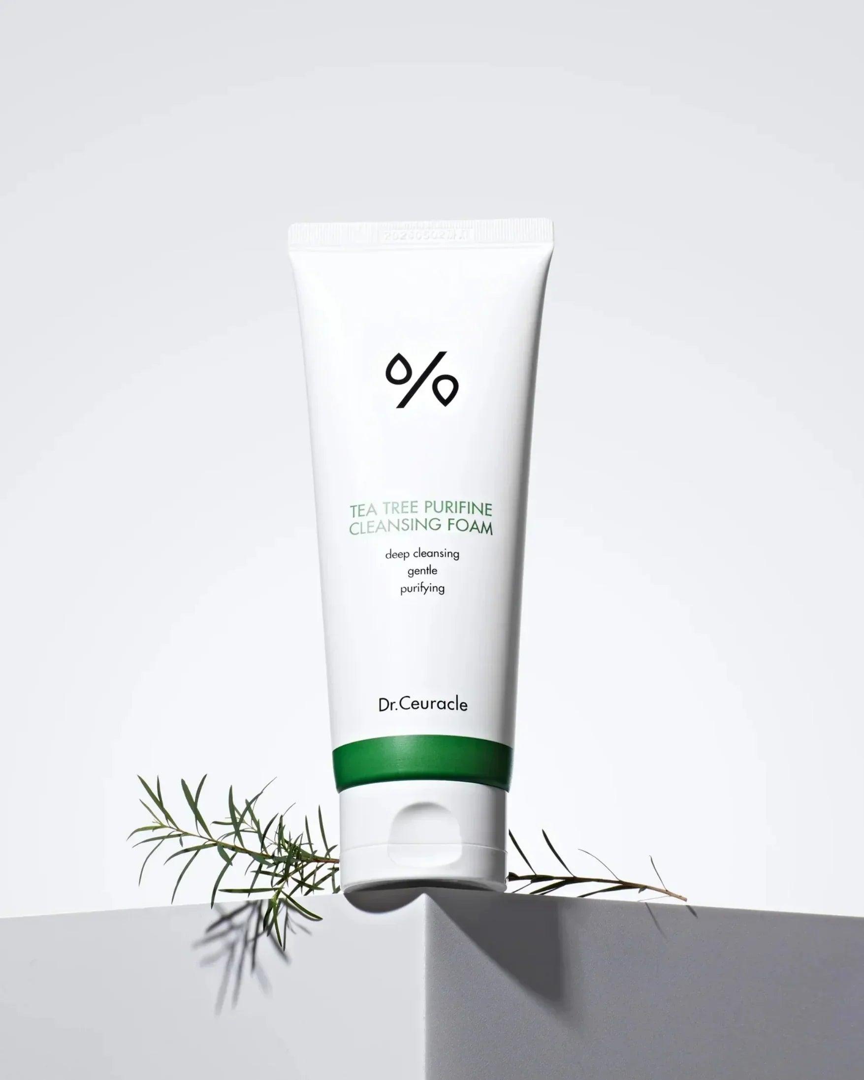 Dr. Ceuracle Tea Tree Purifine Cleansing Foam tube on white geometric surface with green leaf sprig