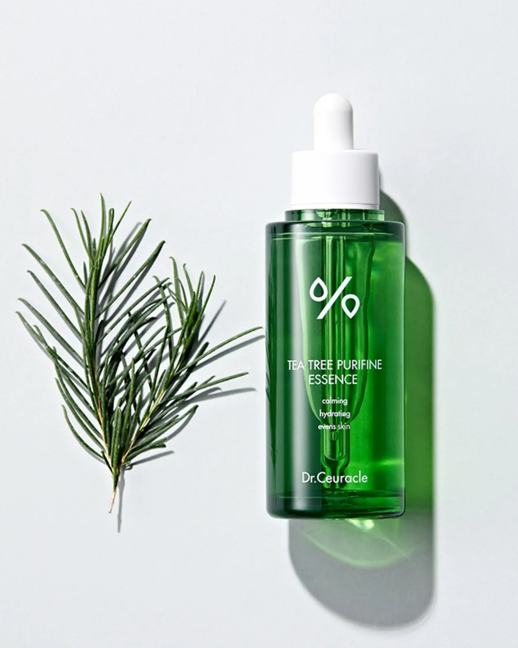 Green glass bottle of Dr. Ceuracle Tea Tree Purifine Essence with dropper and tea tree branch