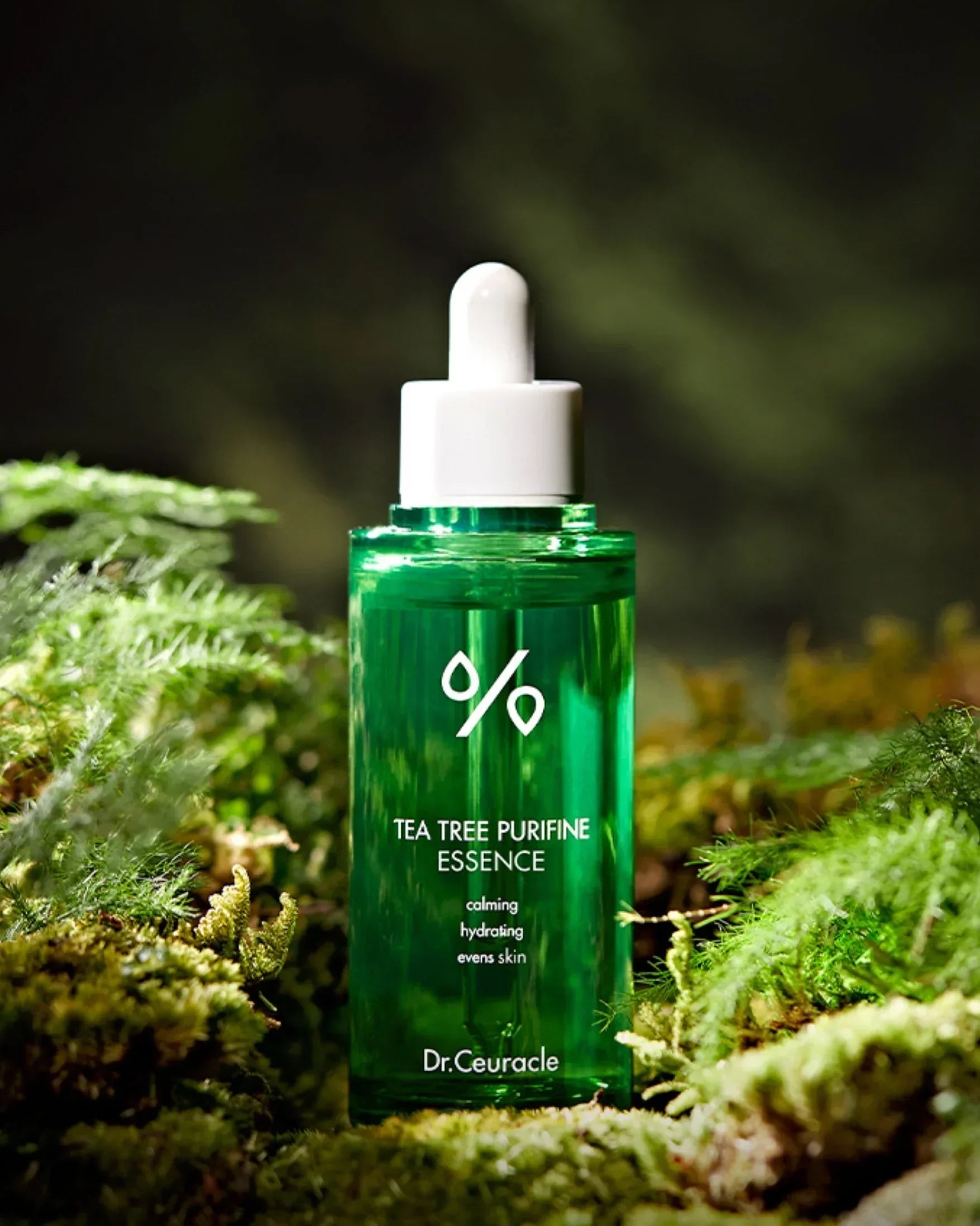 Green glass dropper bottle of Dr. Ceuracle Tea Tree Purifine Essence on moss with blurred natural background