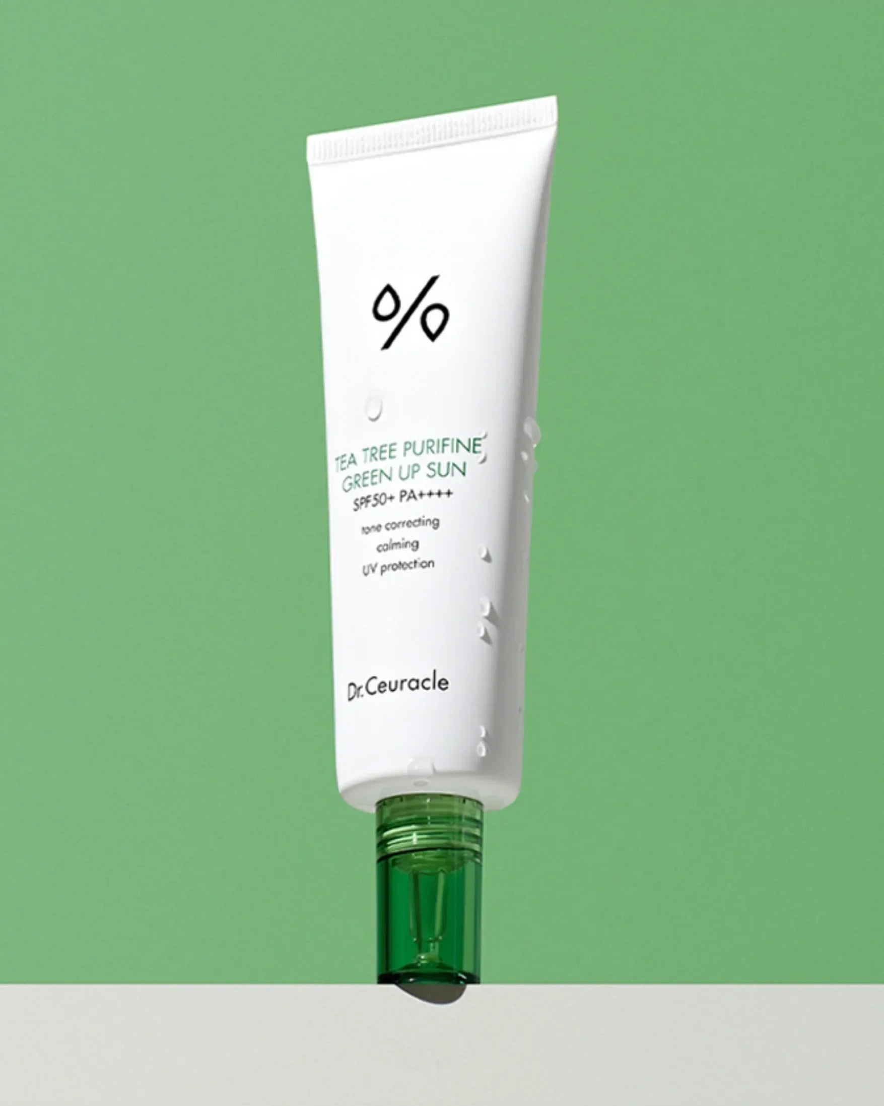 Dr. Ceuracle Tea Tree Purifine Green Up Sun SPF50+ PA++++ sunscreen tube with water droplets on green background