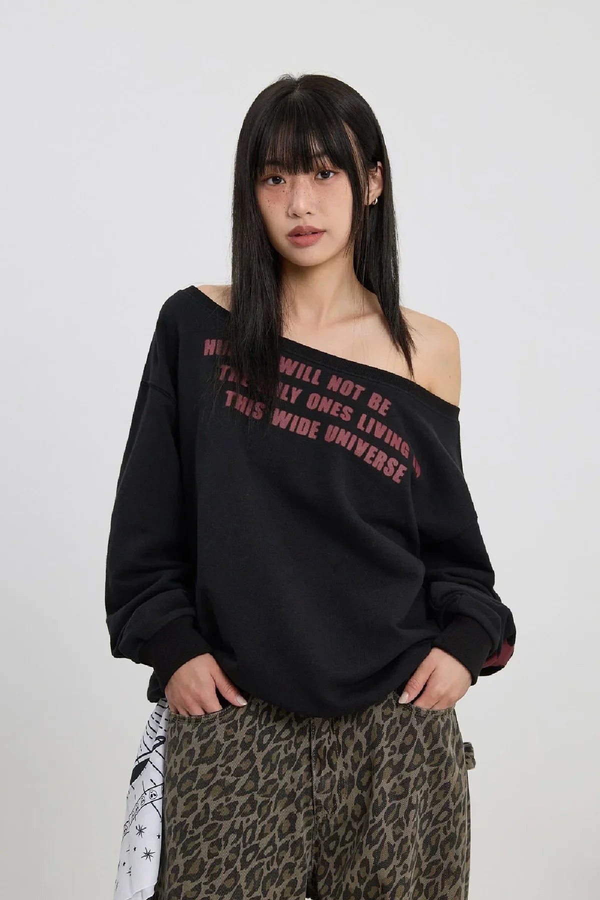 Woman wearing black off-shoulder sweatshirt with red text and leopard print pants