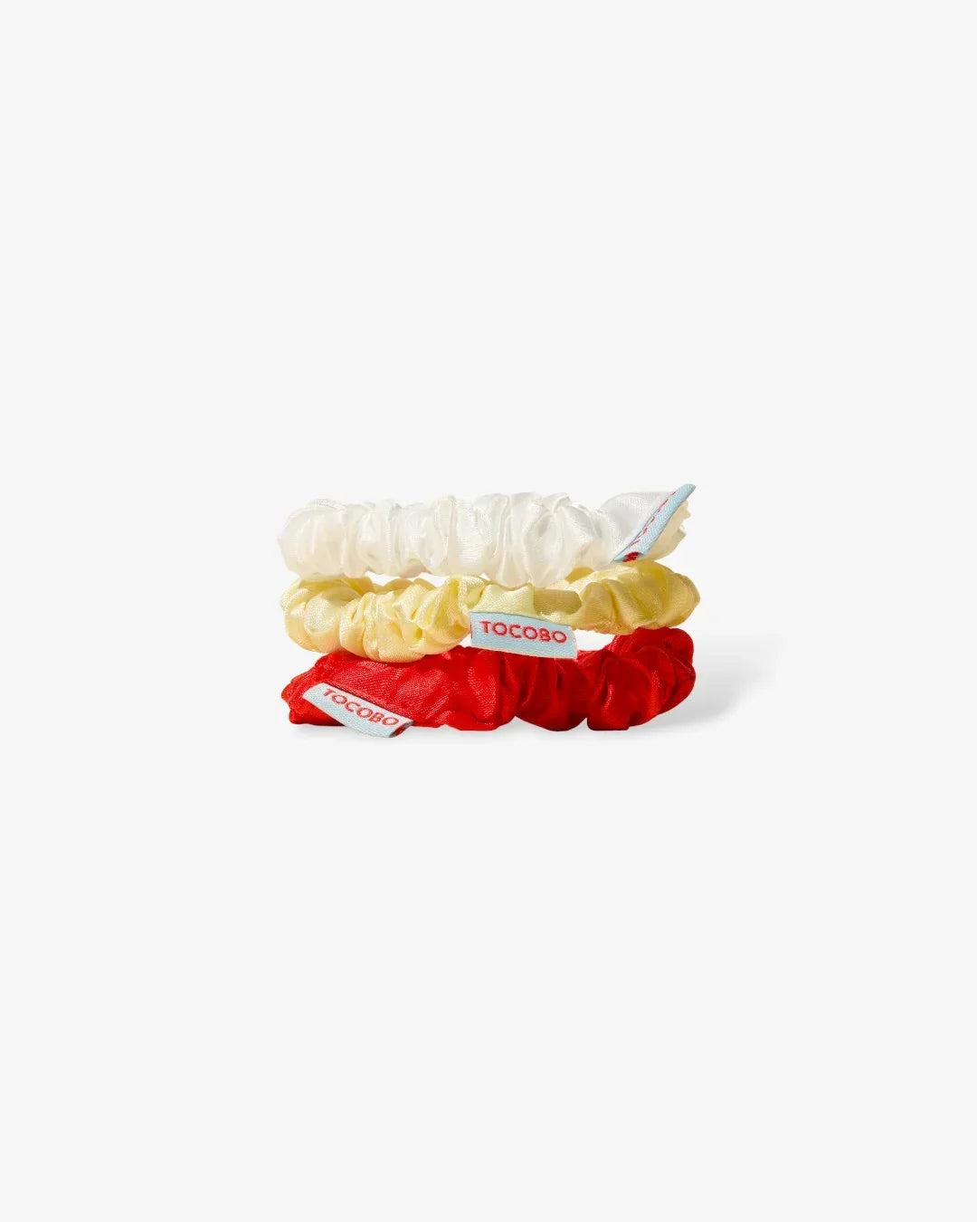 Set of three satin hair scrunchies in white, yellow, and red with TOCOBO tags