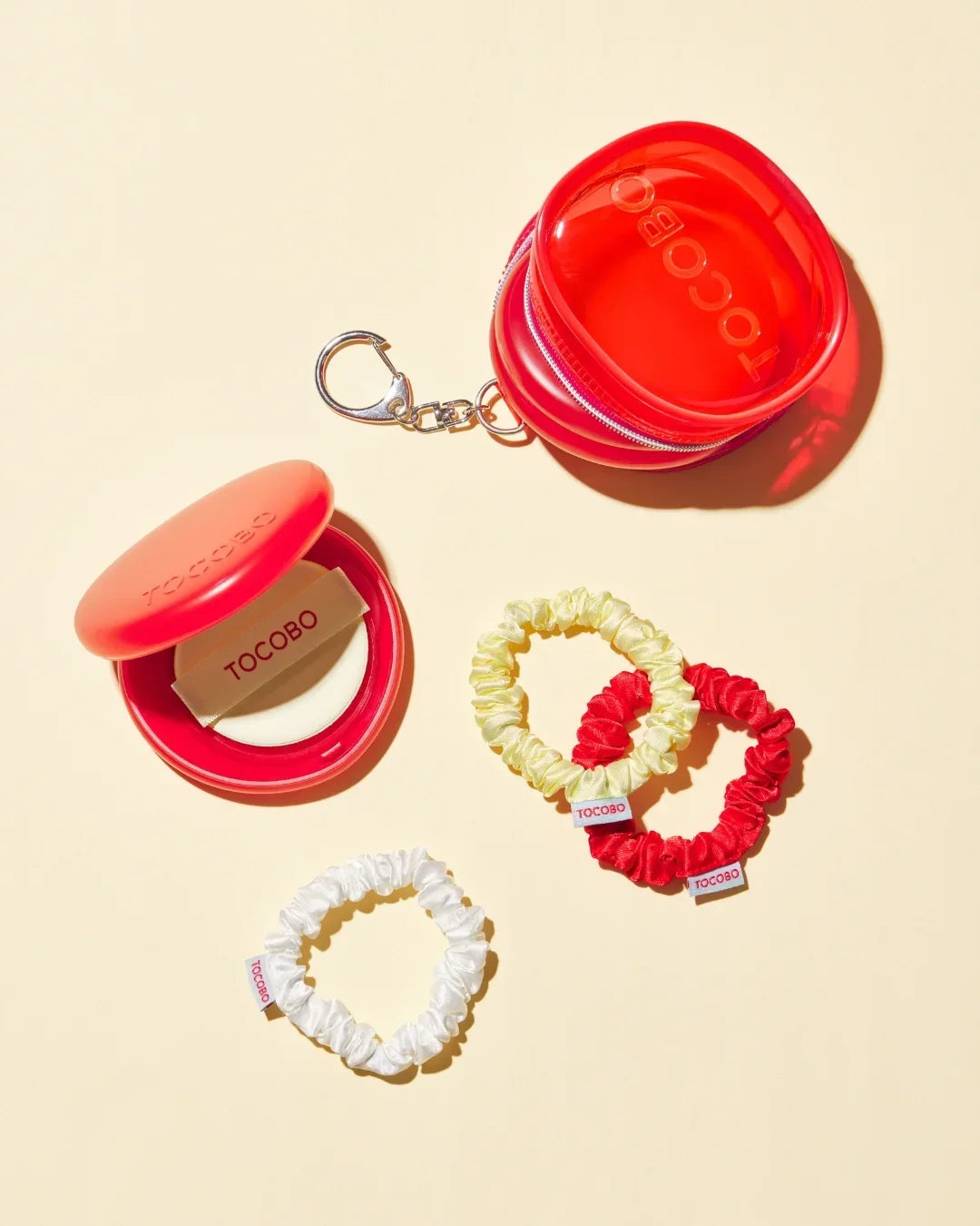 Red TOCOBO hair scrunchie case with keychain, open compact, and three satin scrunchies in yellow, red, and white