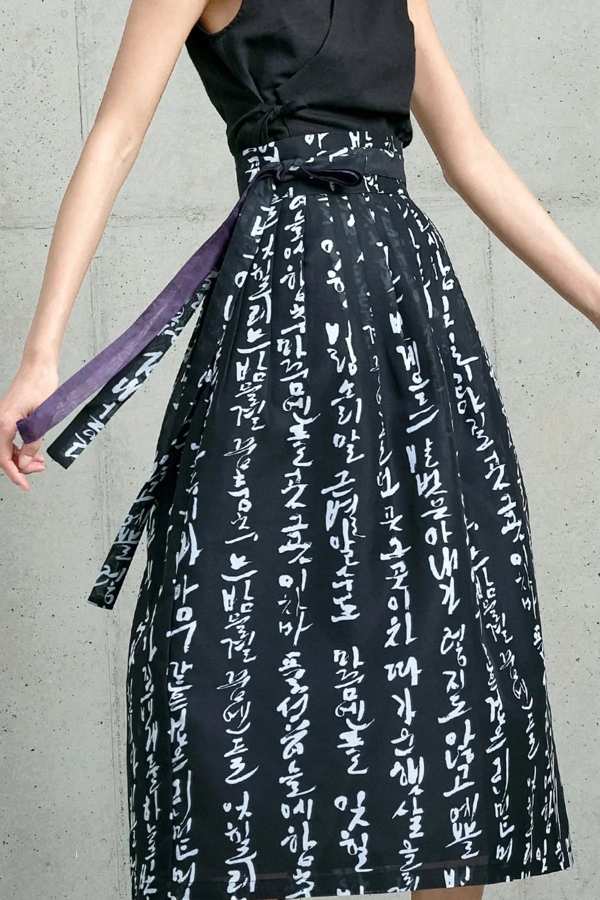 Close-up of black traditional Korean skirt with white Hangeul script and tied sash