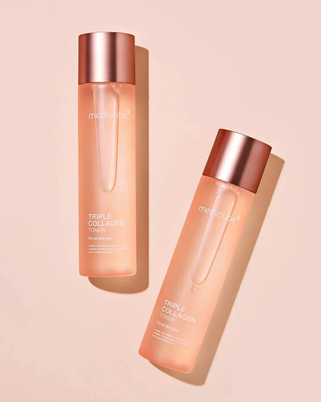 Two Medicube Triple Collagen Toner bottles with rose gold caps on a beige background