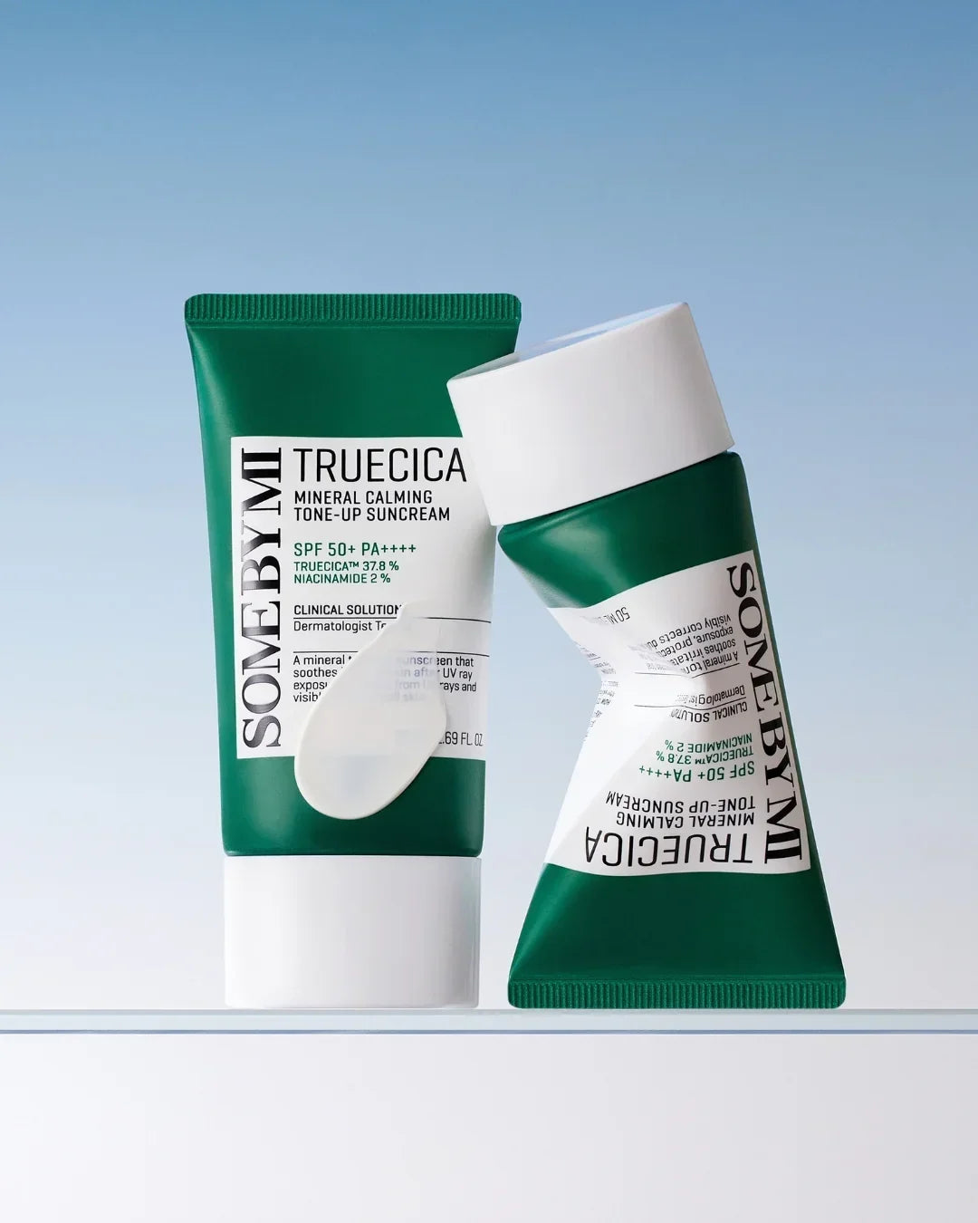 Two green tubes of SOME BY MI TRUECICA Mineral Calming Tone-Up Suncream SPF 50+ PA++++ against a blue background