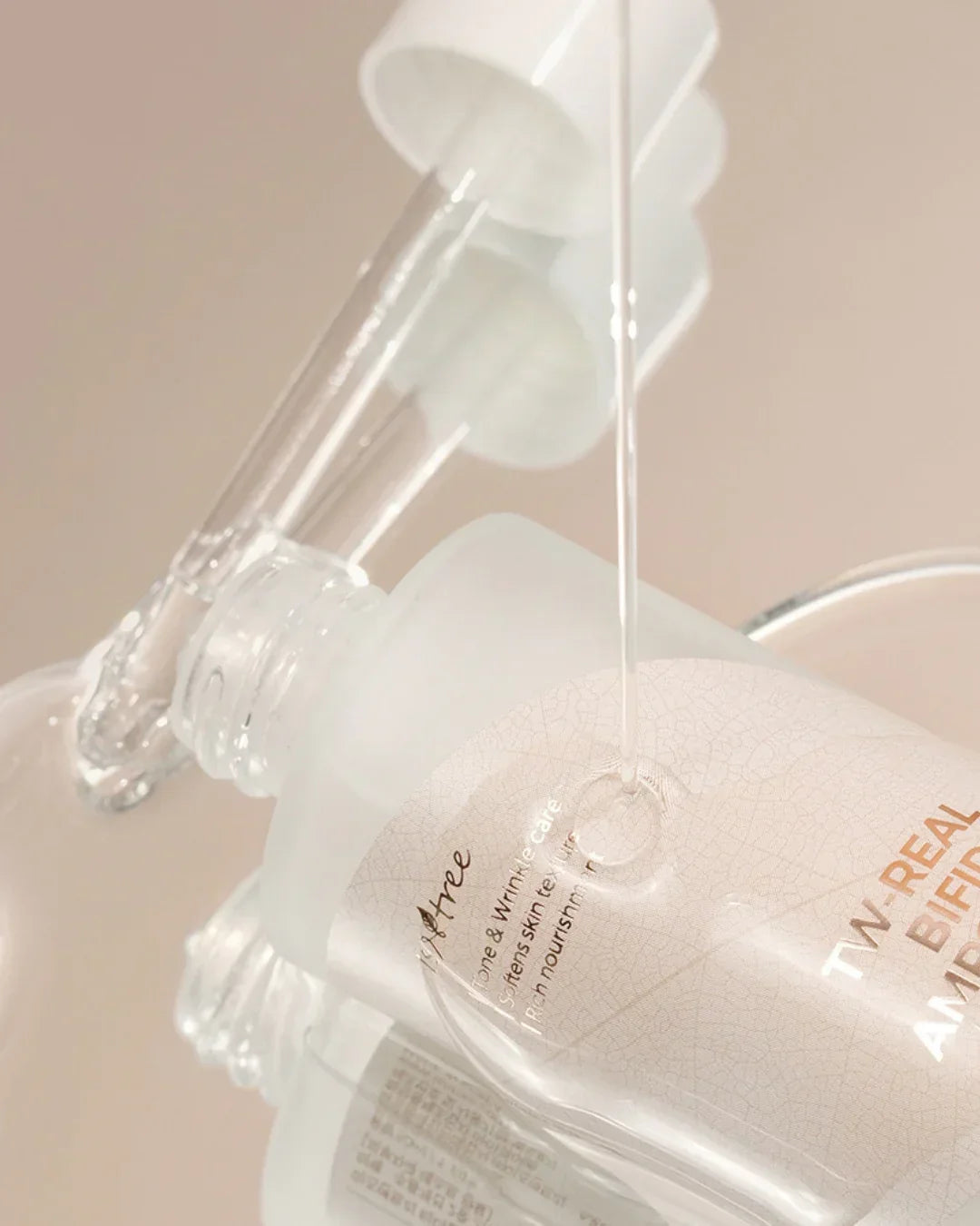 Clear serum dropper dispensing liquid onto frosted bottle of TN Real Bifida Ampoule skincare