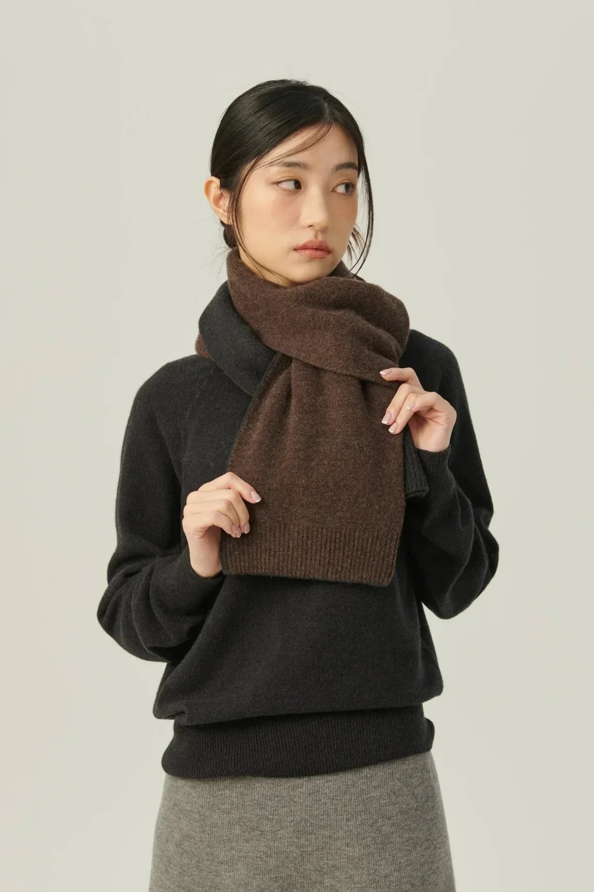 Woman wearing two-tone brown cashmere muffler scarf with black sweater and grey skirt