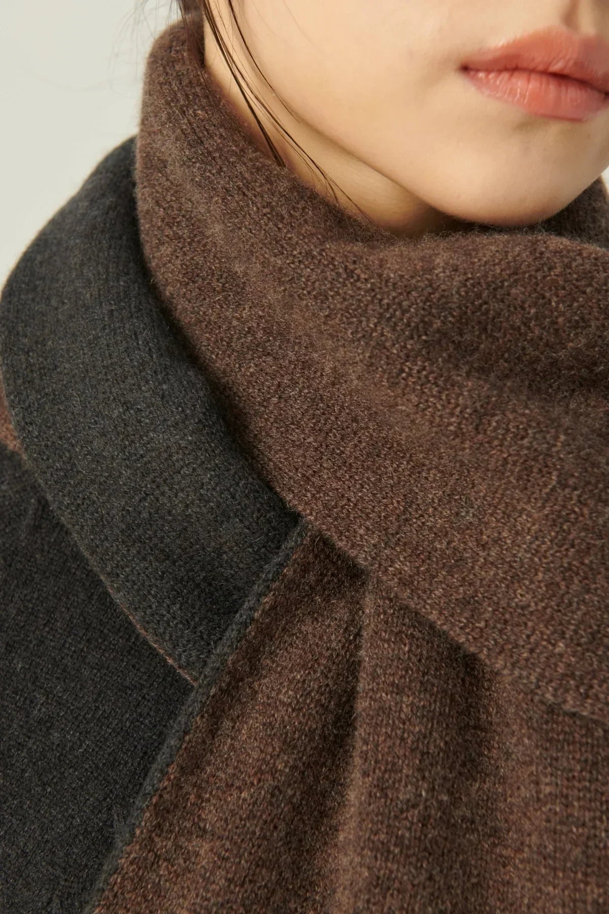 Close-up of a two-tone cashmere muffler in brown and dark gray wrapped around a woman's neck