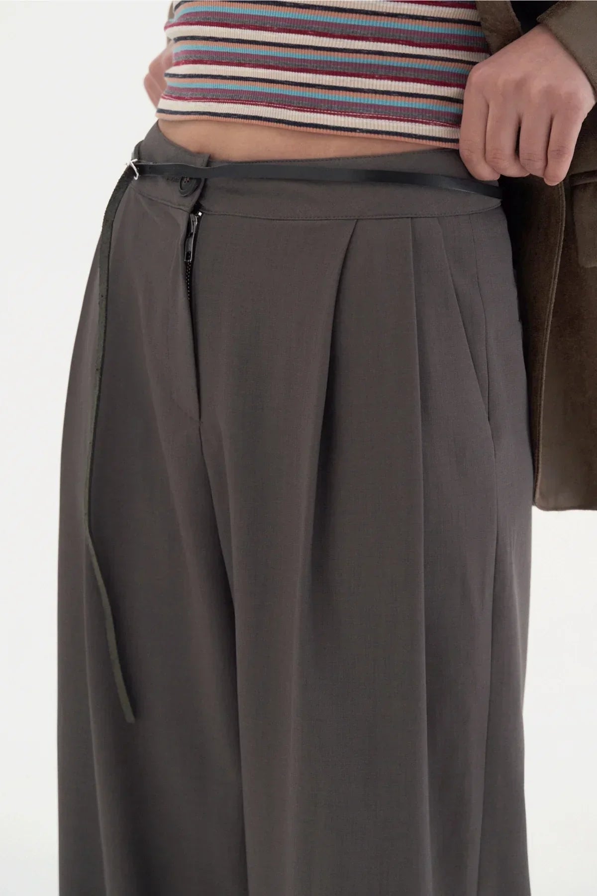 Close-up of two-tuck wide dark gray slacks with black belt and striped crop top