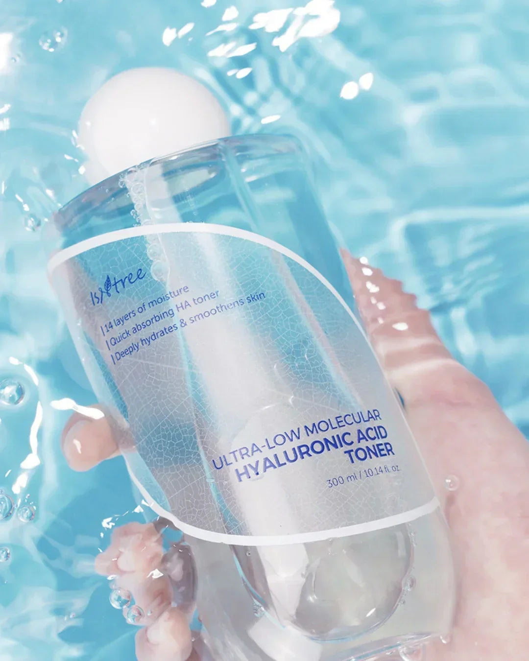 Hand holding Isntree Ultra-Low Molecular Hyaluronic Acid Toner bottle in clear blue water