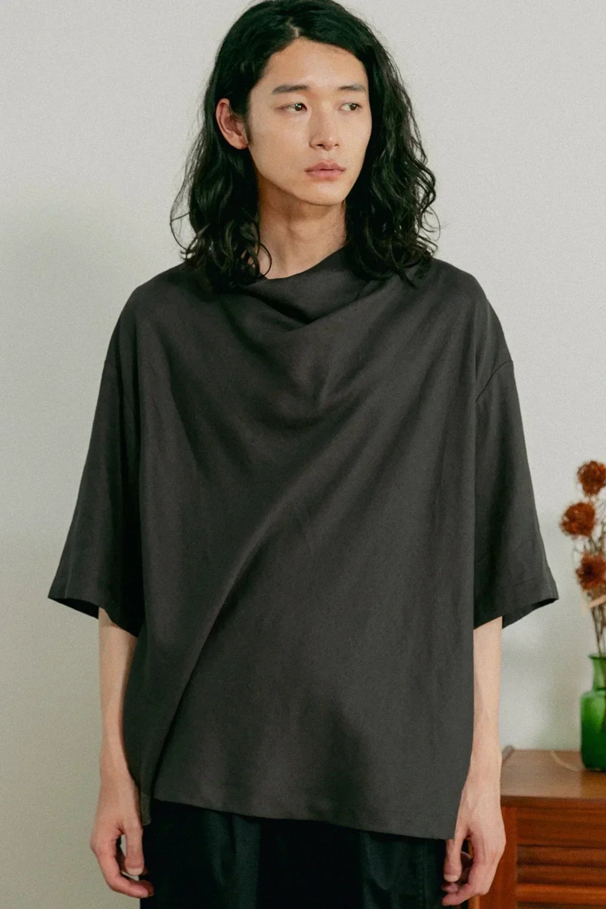 Man wearing loose dark gray cowl neck t-shirt with short sleeves indoors