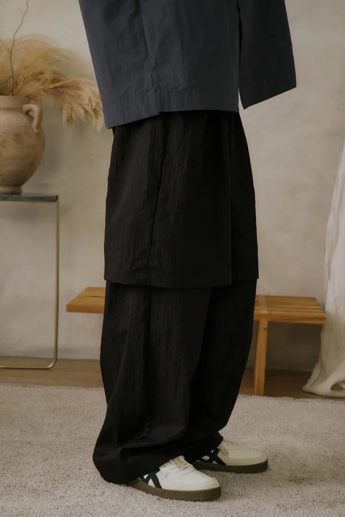 Close-up of unisex black layered see-through pants worn with white sneakers indoors
