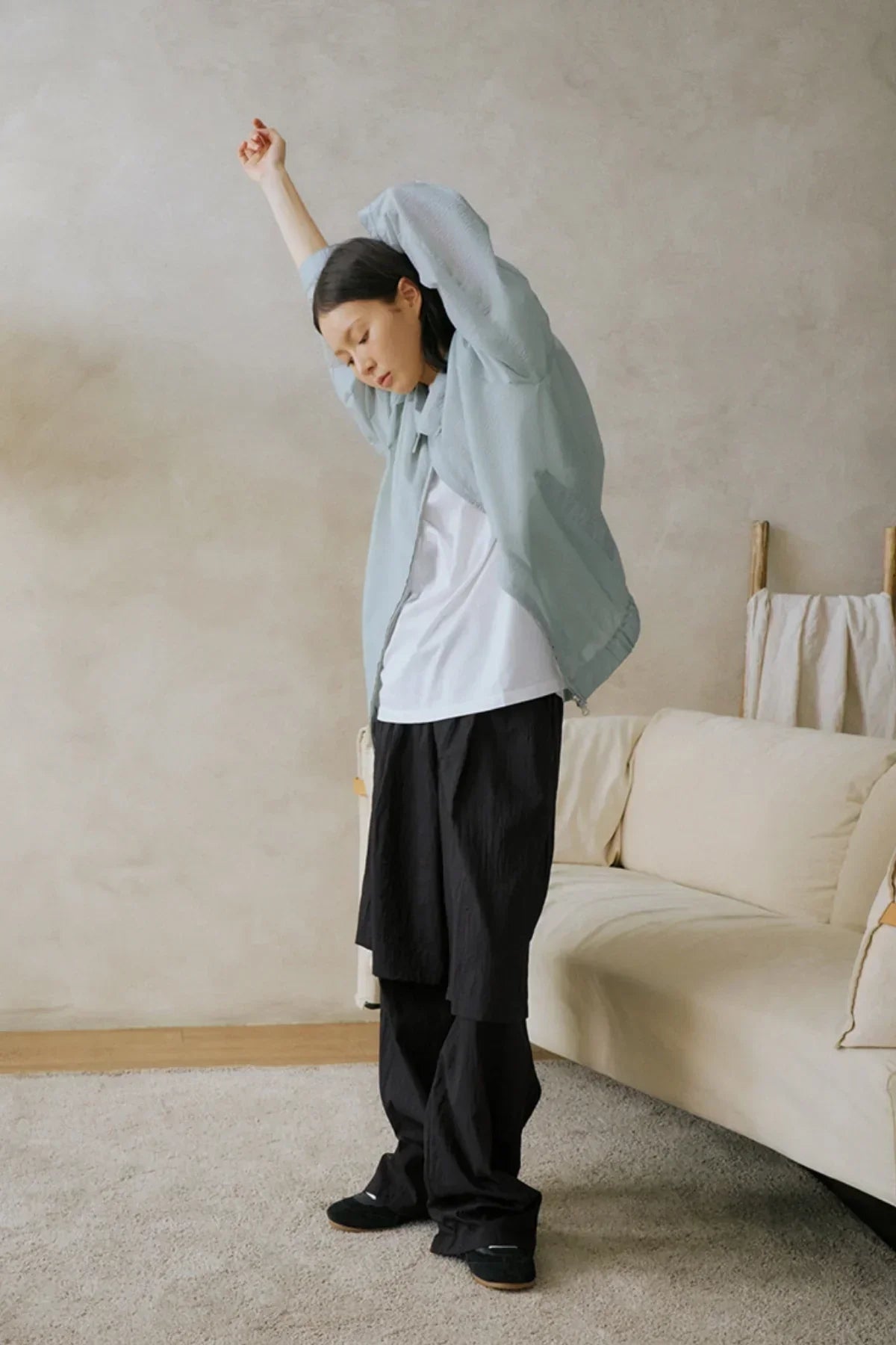 Model wearing black unisex see-through layered pants with white shirt and light blue jacket in living room