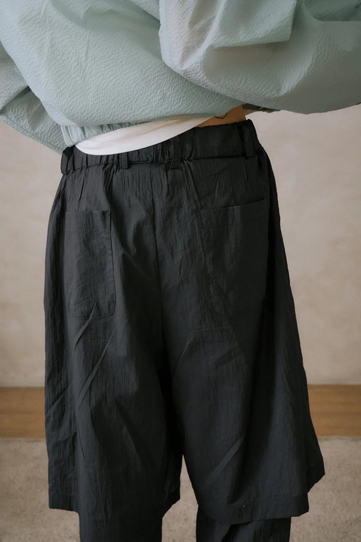 Close-up of unisex black layered pants with pockets and elastic waistband