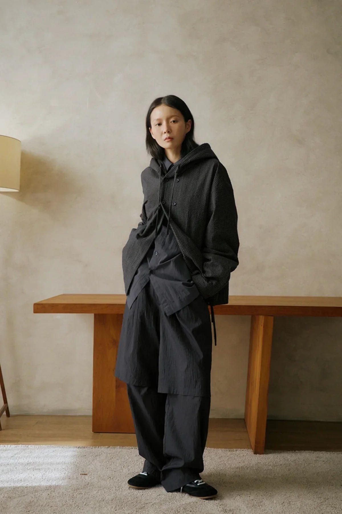 Young woman wearing black layered unisex streetwear outfit with oversized hoodie and pants indoors