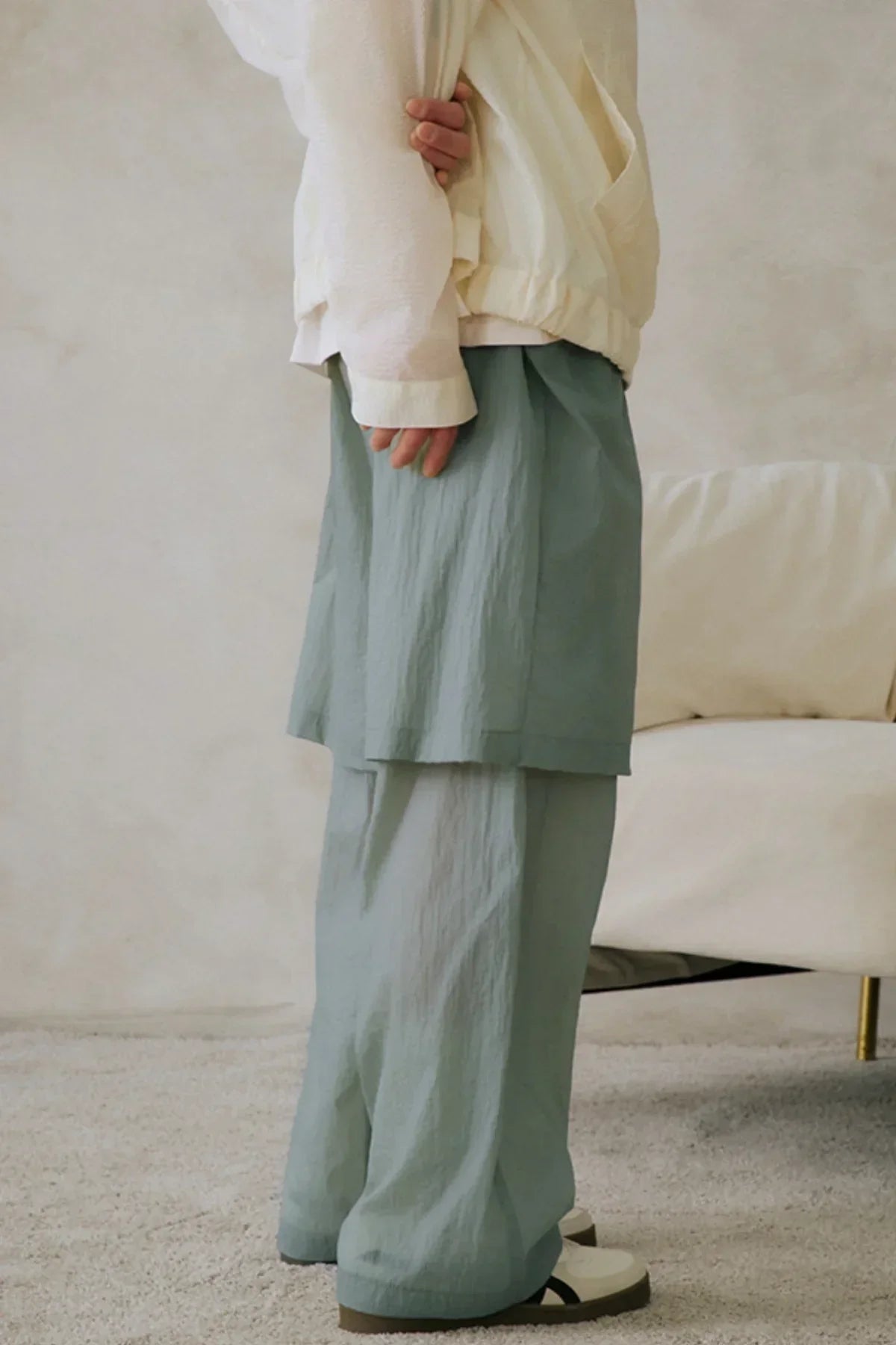 Close-up of unisex mint seethrough layered pants worn with white sneakers indoors