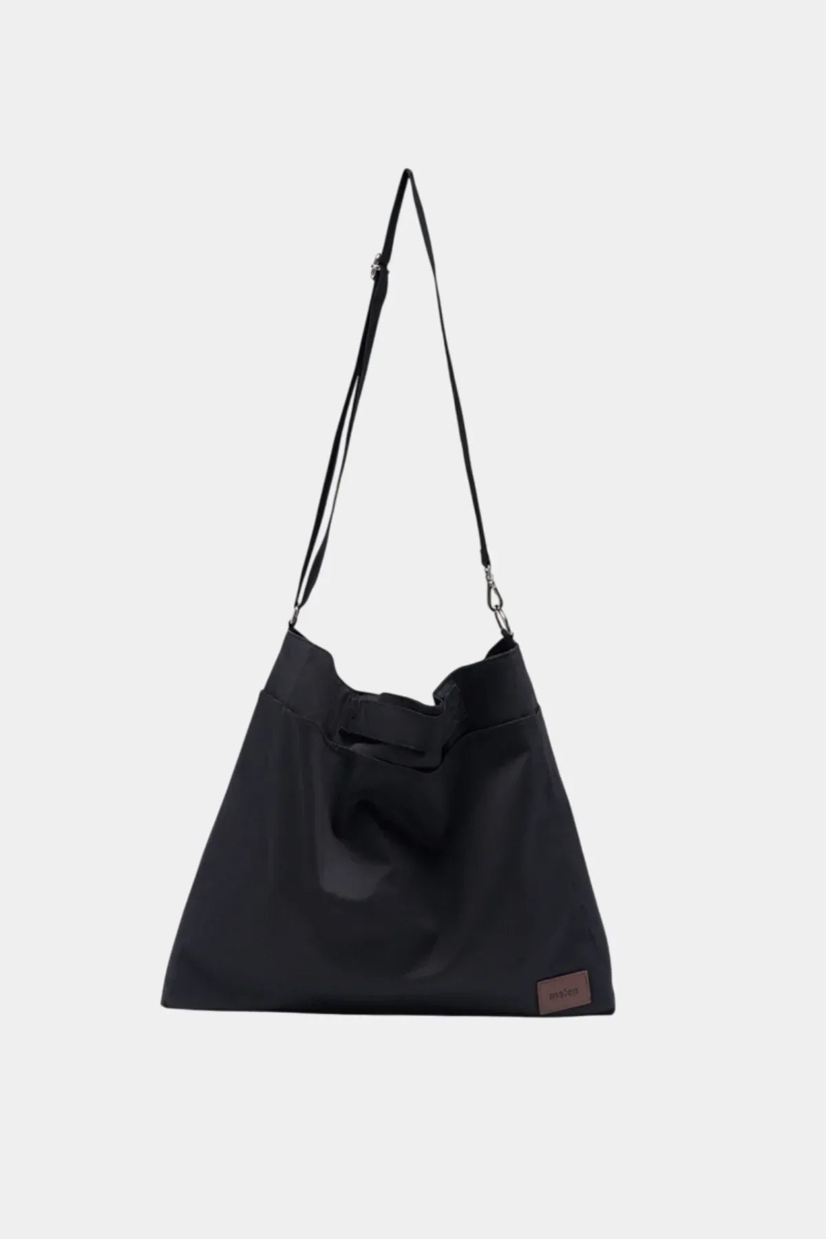 Black unisex shoulder bag with adjustable strap and small brown logo patch on front