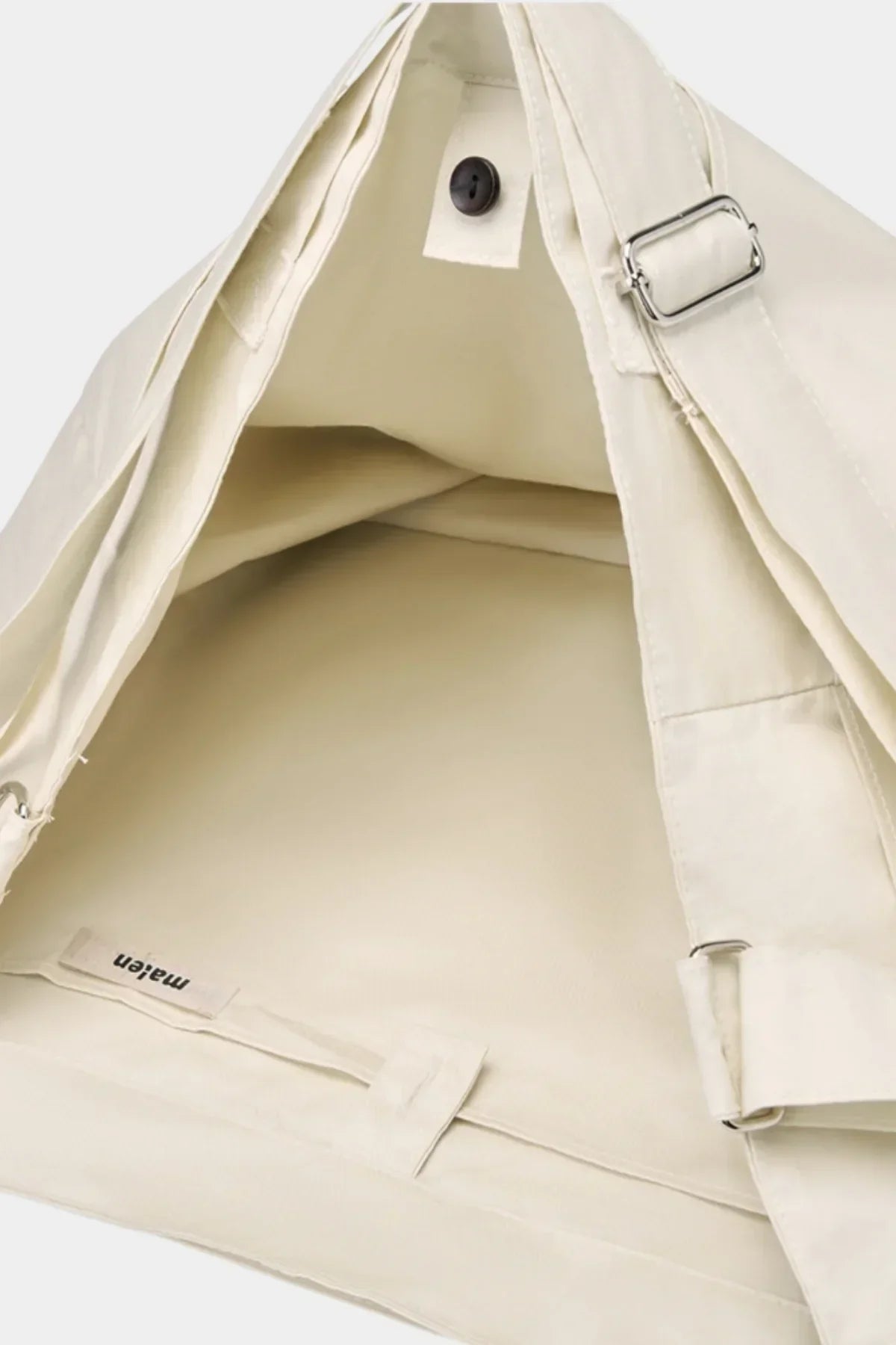 Close-up of cream-colored unisex shoulder bag interior with button closure and adjustable strap