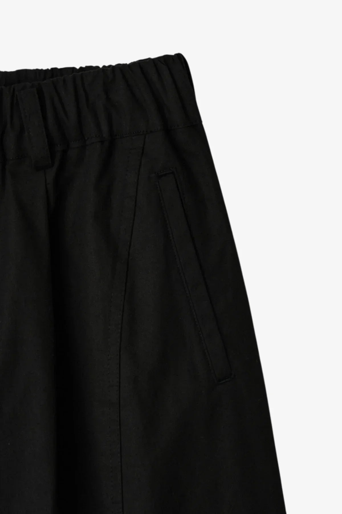 Close-up of black side seam pants with elastic waistband and angled front pocket
