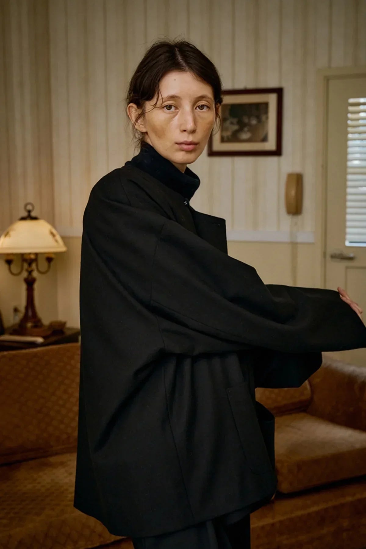 Woman wearing a black unisex wool loop jacket in a vintage-style living room