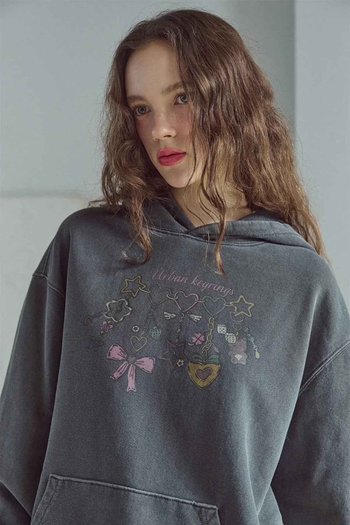 Close-up of woman wearing gray pigment hoodie with Urban keyrings graphic design