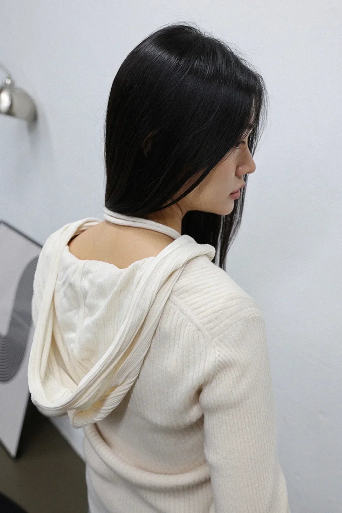 Woman with long black hair wearing an ivory ribbed knit hoodie indoors