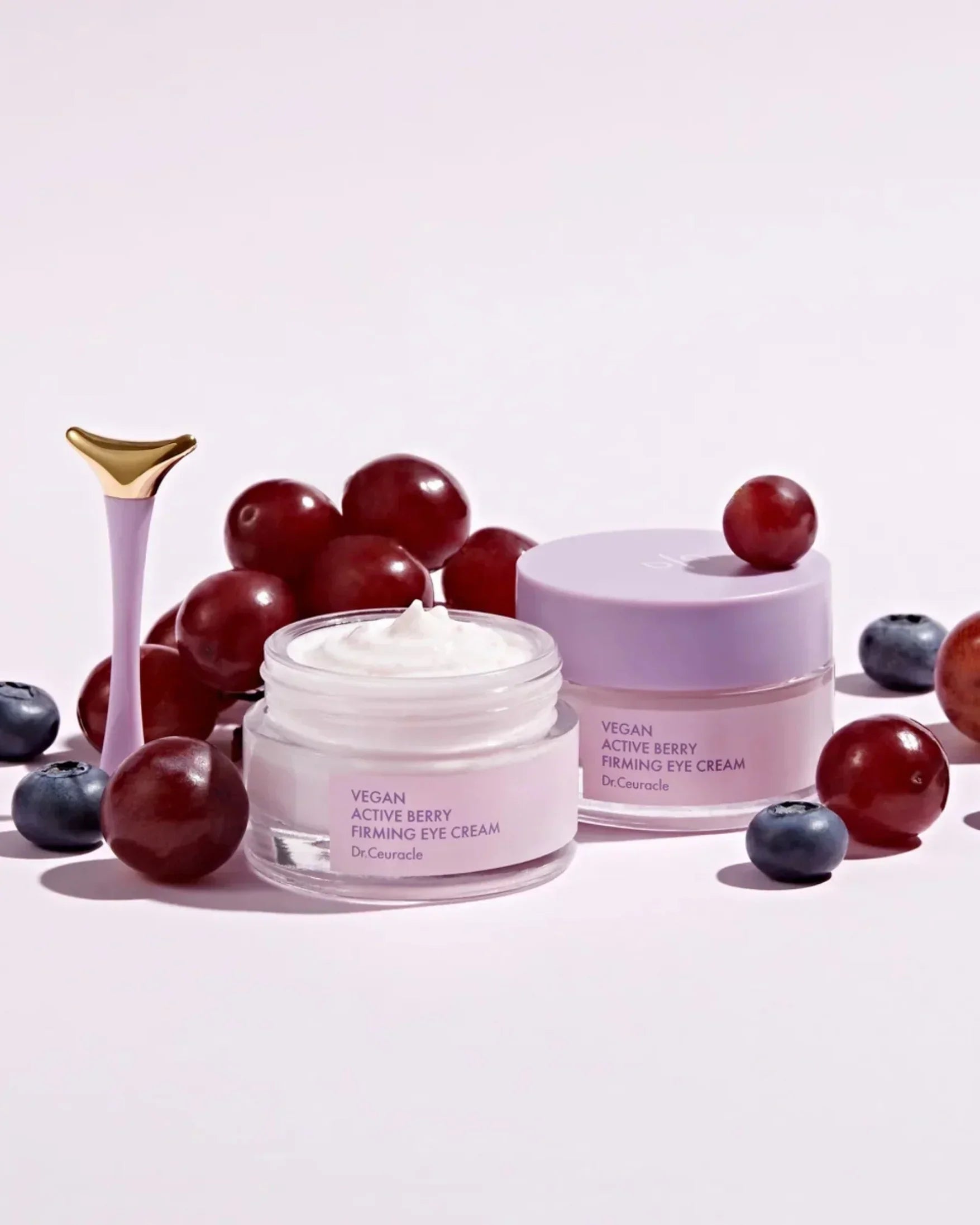 Dr.Ceuracle Vegan Active Berry Firming Eye Cream jars with fresh blueberries and red grapes on white background