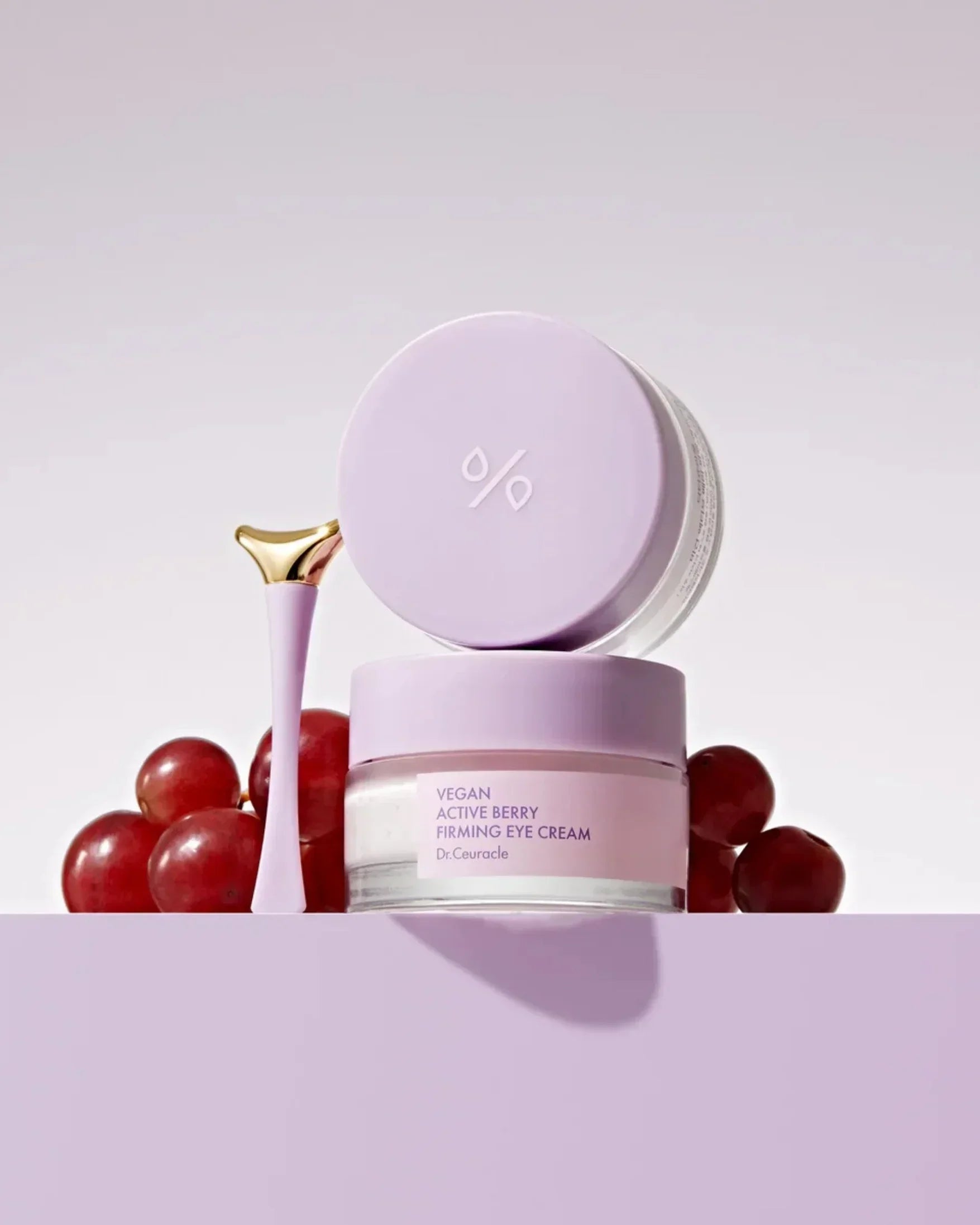 Dr.Ceuracle Vegan Active Berry Firming Eye Cream jar with applicator and grapes on soft purple background
