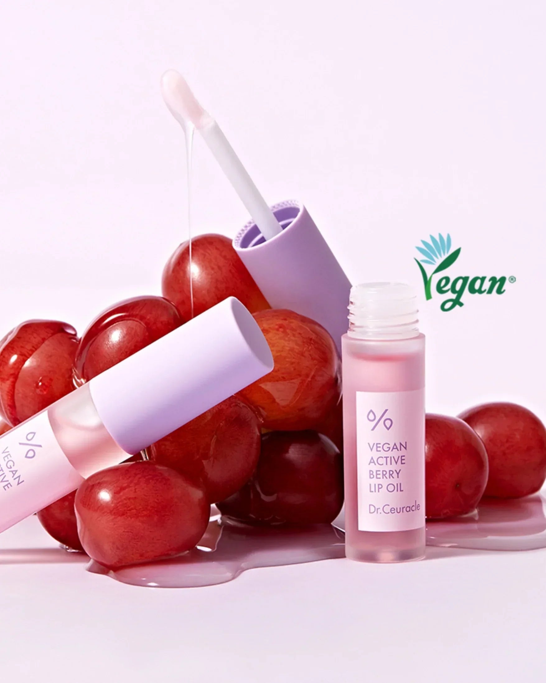 Dr.Ceuracle Vegan Active Berry Lip Oil with applicator and fresh red berries on a pink background