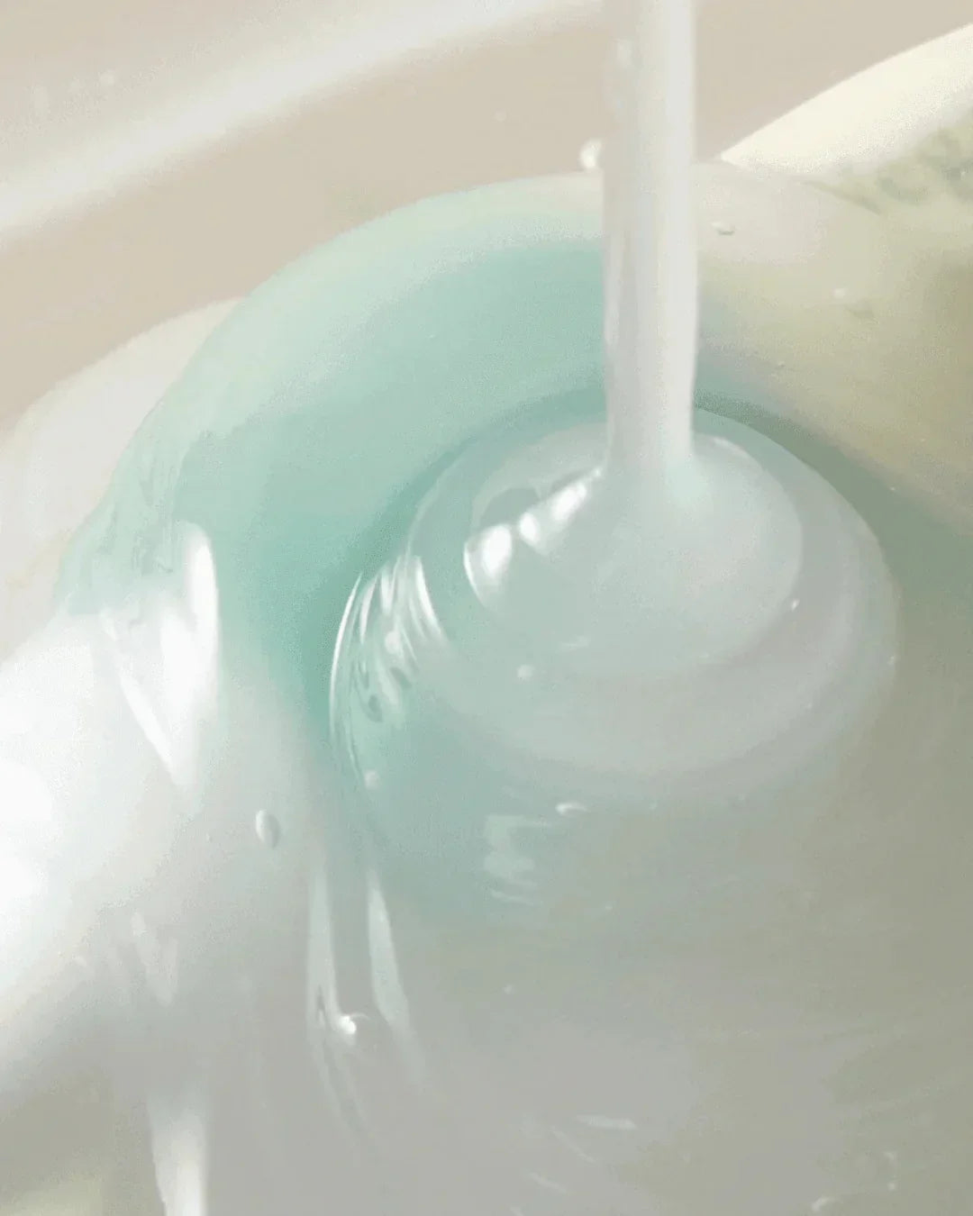 Close-up of vegan collagen eye serum with milky texture pouring into a light container