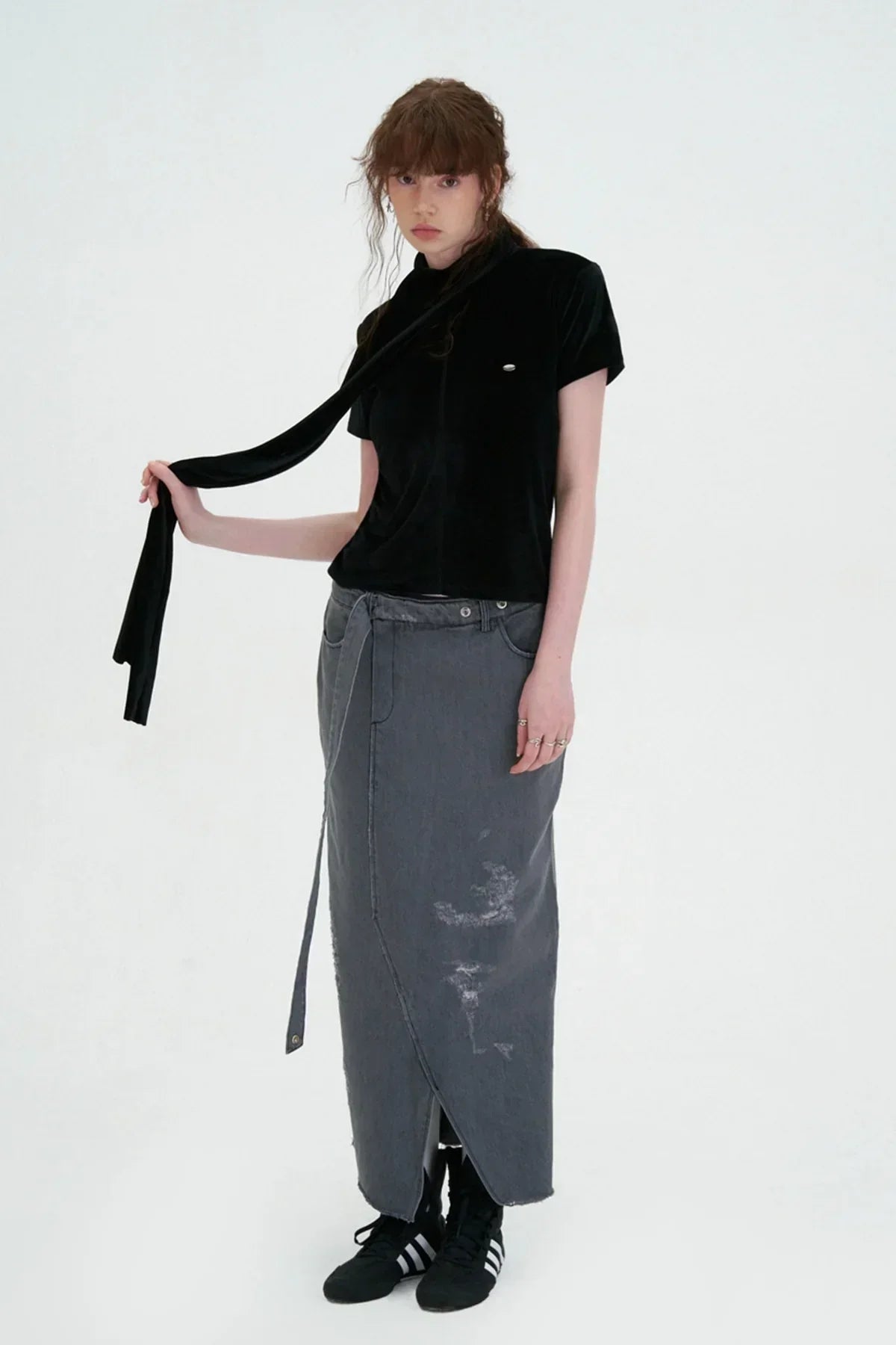 Model in studio wearing black velvet top with scarf and gray distressed maxi skirt with Adidas sneakers