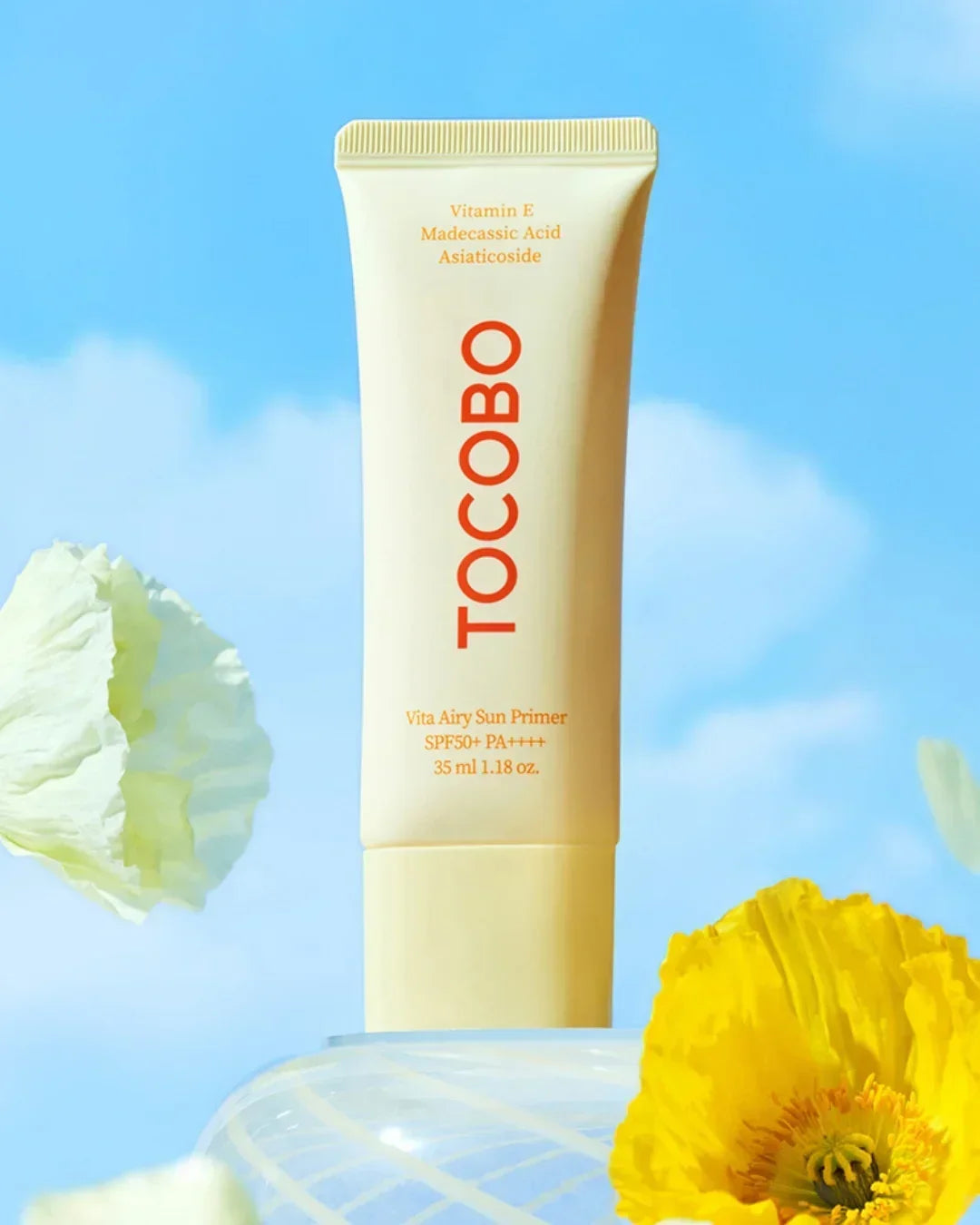 TOCOBO Vita Airy Sun Primer SPF50 PA++++ tube with Vitamin E, Madecassic Acid on blue sky background with flowers