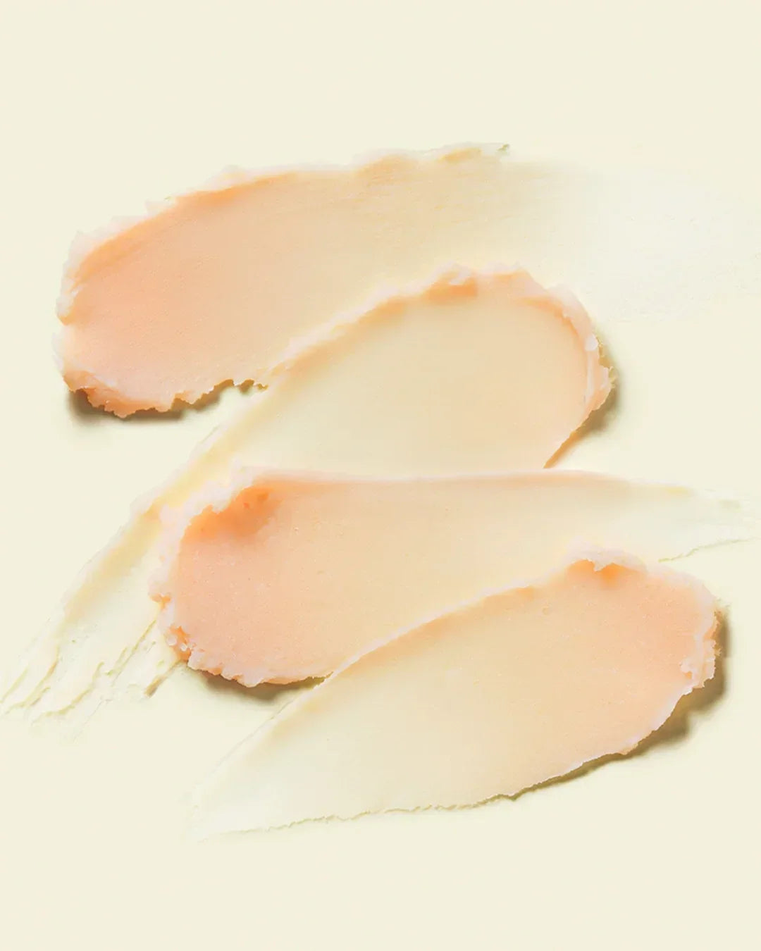 Creamy beige and peach cosmetic primer texture swatches on light background