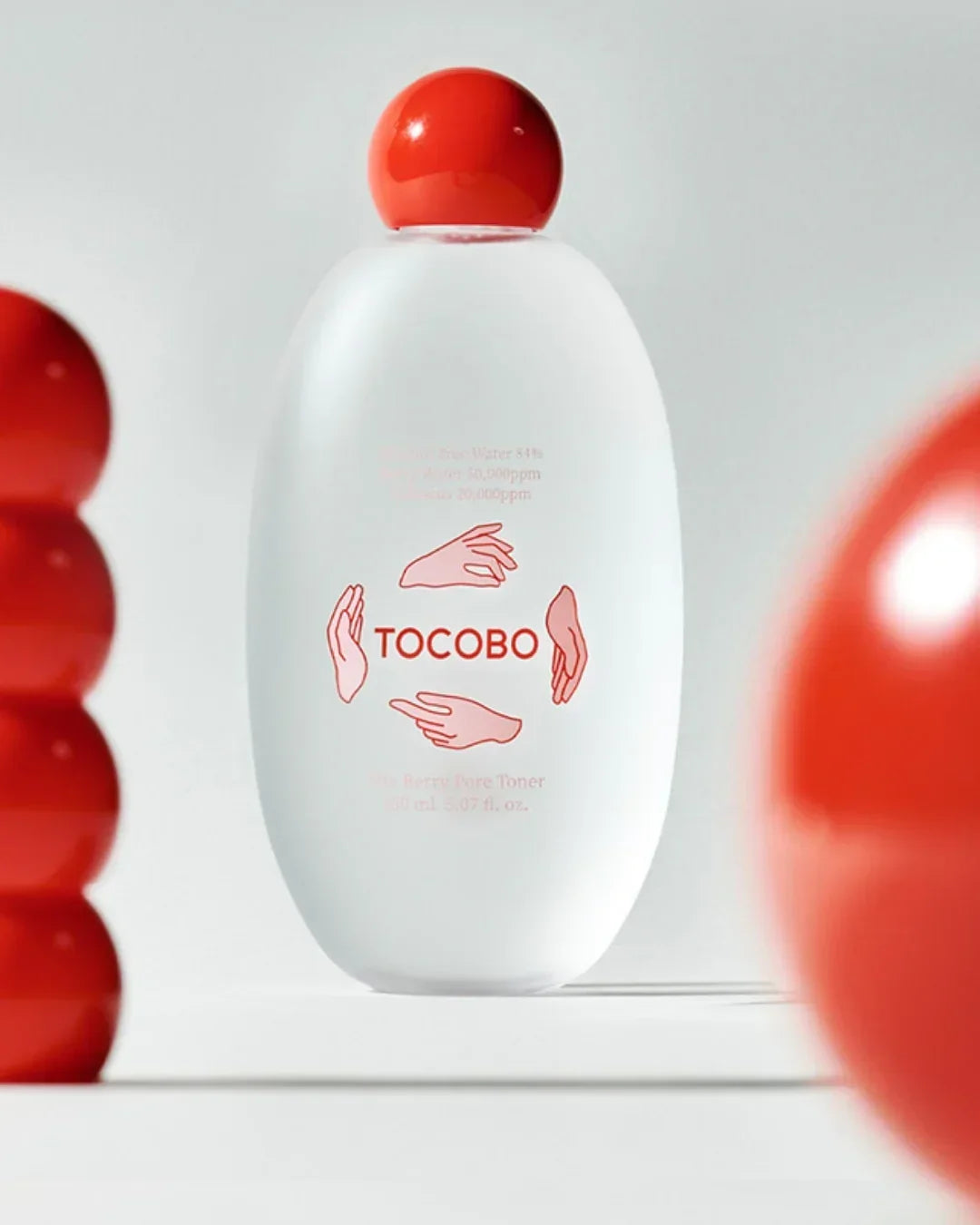White TOCOBO Vita Berry Pore Toner bottle with red cap on white background, surrounded by red spheres