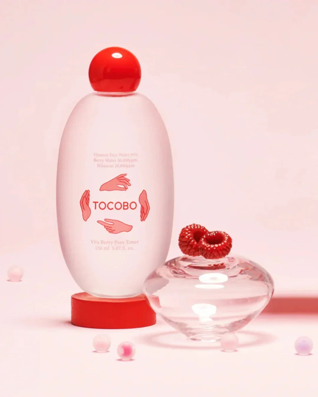 Tocobo Vita Berry Pore Toner bottle with red cap on red base, berries on glass dish, pink background