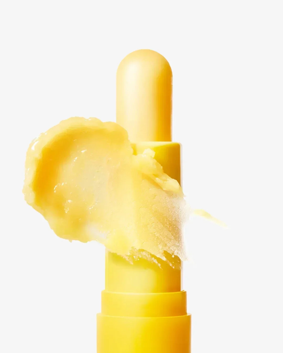 Close-up of yellow vitamin nourishing lip balm stick with creamy textured balm on white background