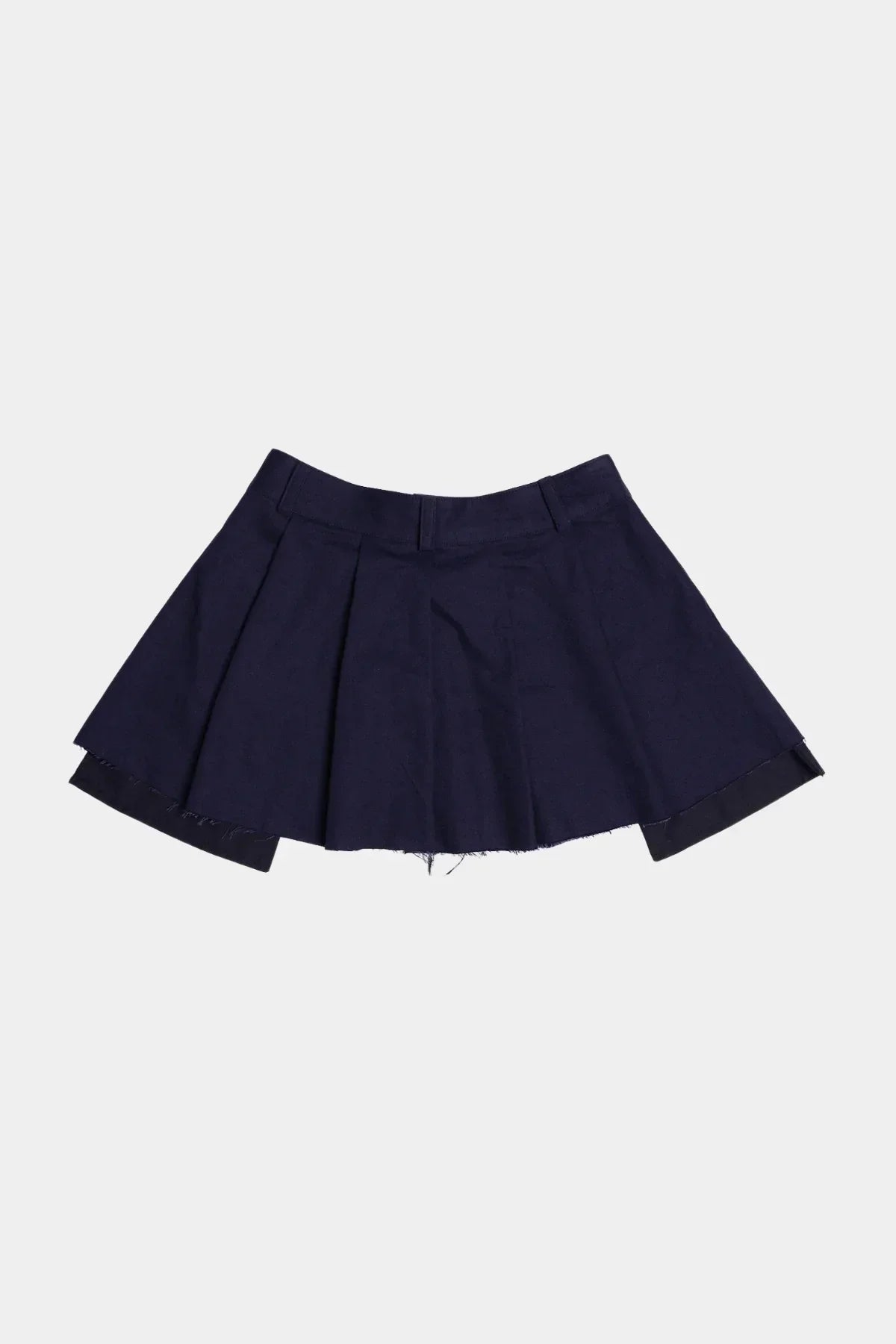 Back view of navy wide tuck mini skirt with raw hem against white background