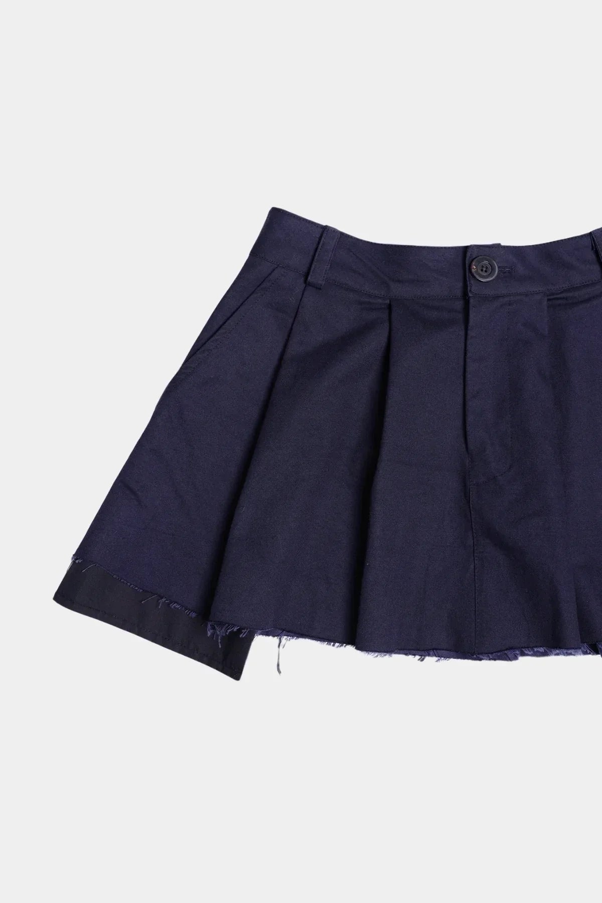 Navy blue wide tuck mini skirt with frayed hem and button closure on white background