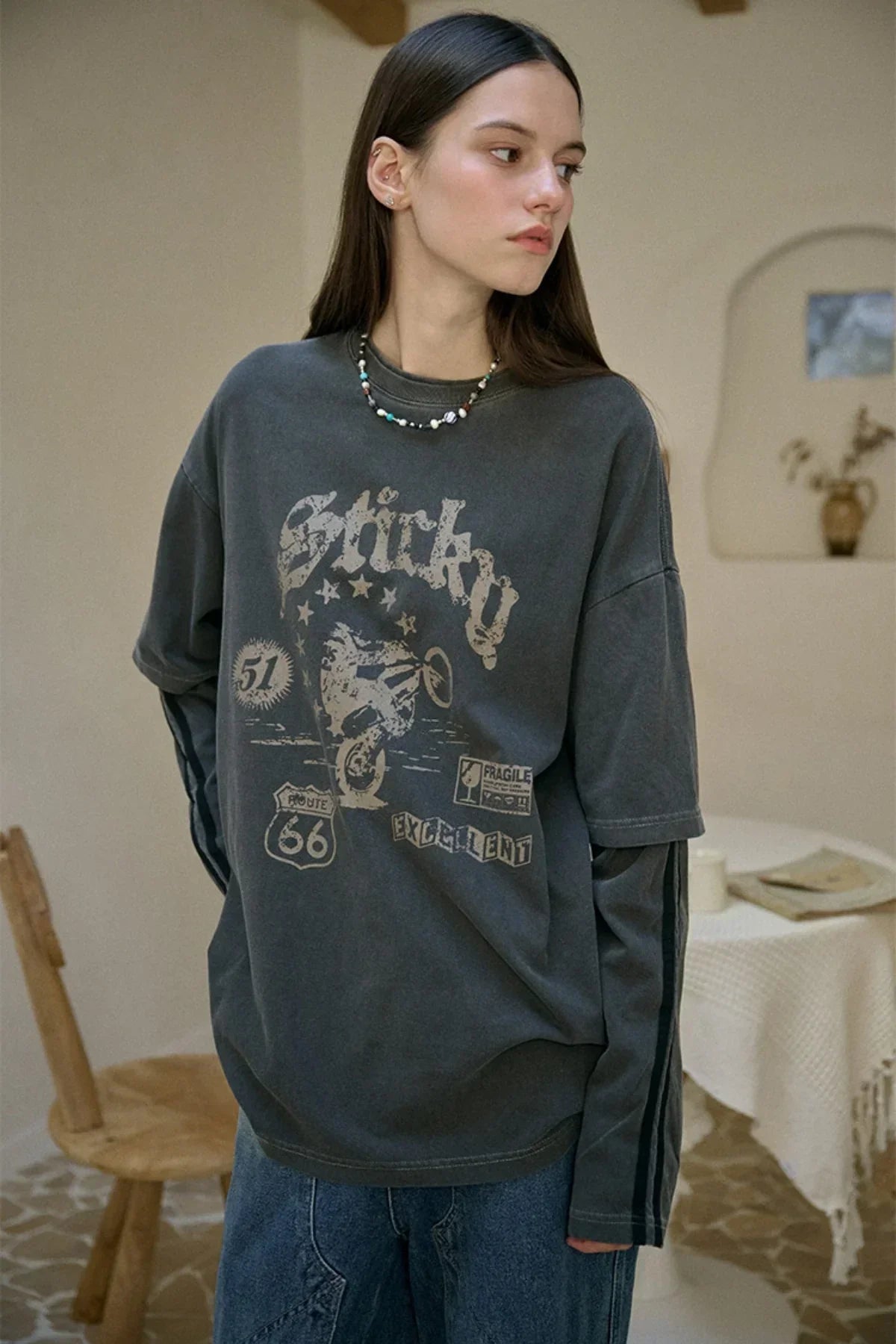 Young woman wearing black layered long-sleeve t-shirt with vintage biker print indoors