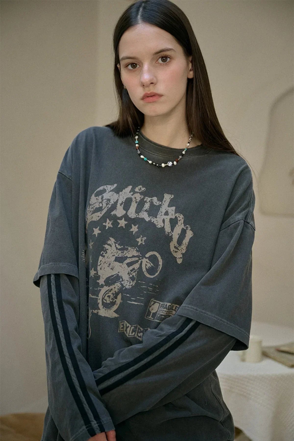 Young woman wearing smoke black layered long sleeve tee with vintage motorcycle graphic and star print