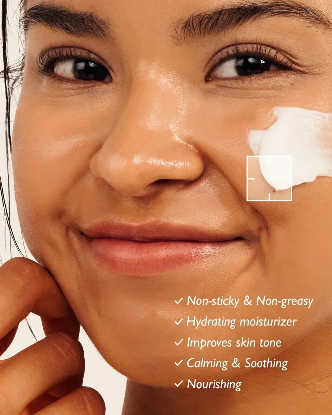 Close-up of smiling woman applying hydrating moisturizer cream on cheek, highlighting calming skincare benefits