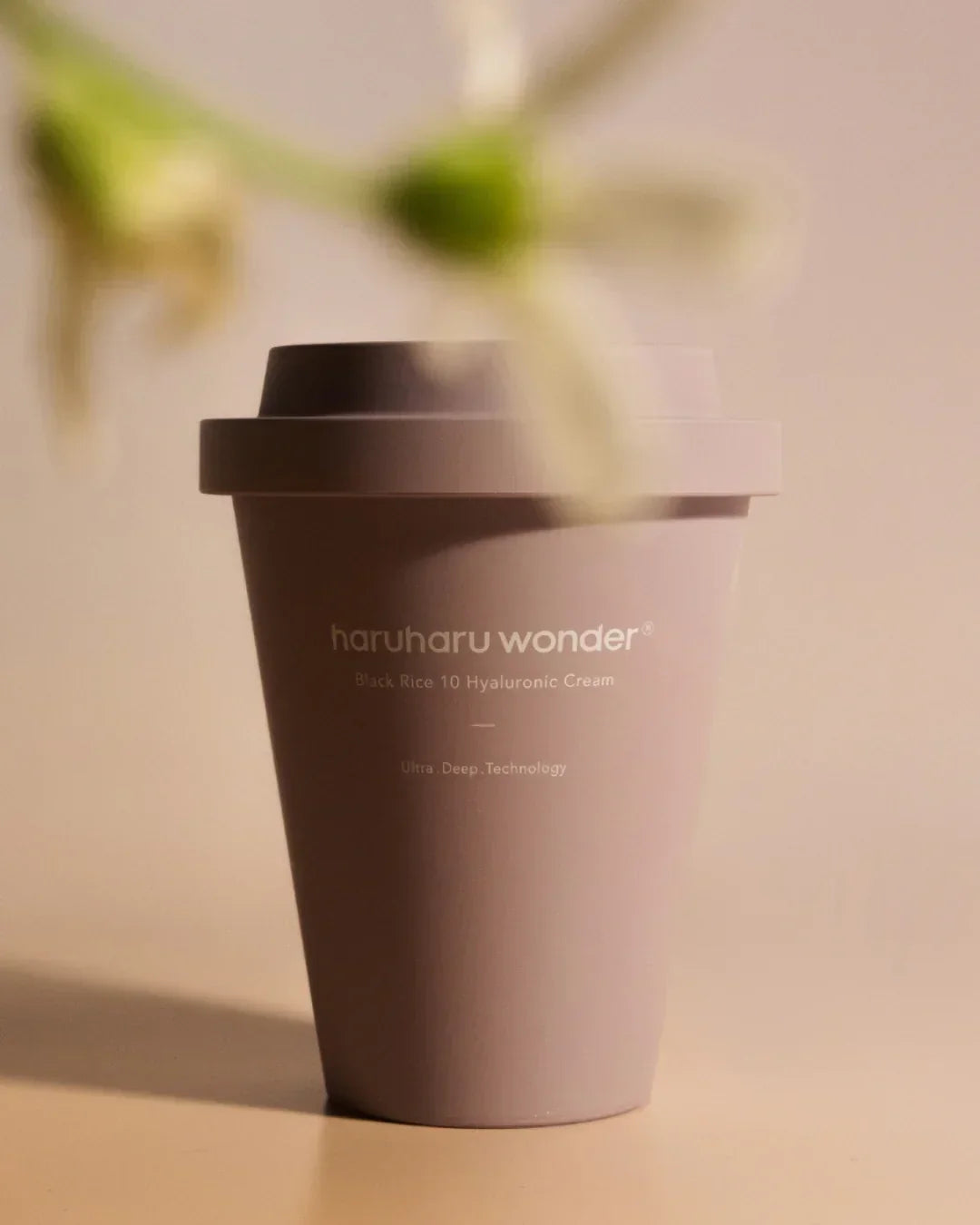 haruharu wonder Black Rice 10 Hyaluronic Cream container on beige surface with blurred flowers