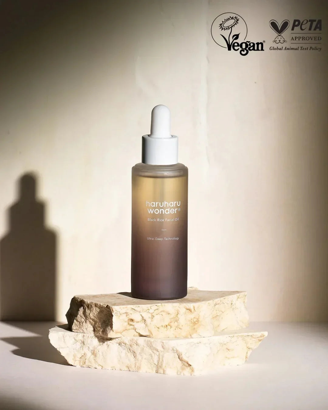 haruharu wonder black rice facial oil bottle on natural stone with vegan and PETA approved logos