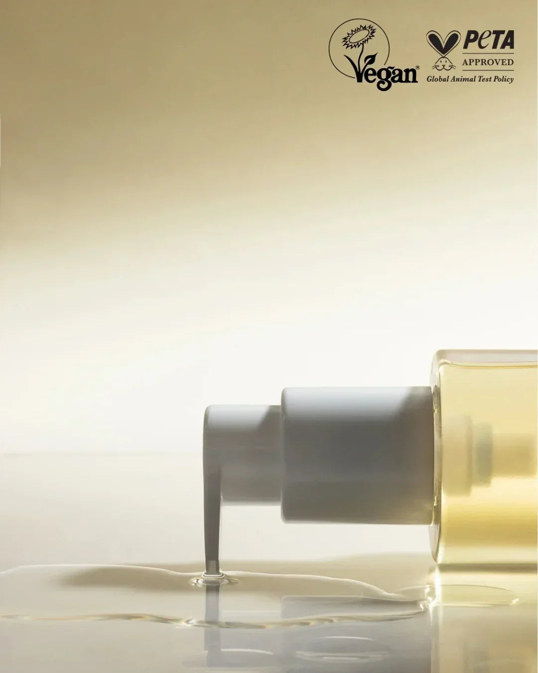 Close-up of clear cleansing oil being dispensed from transparent bottle with white pump, vegan and PETA approved