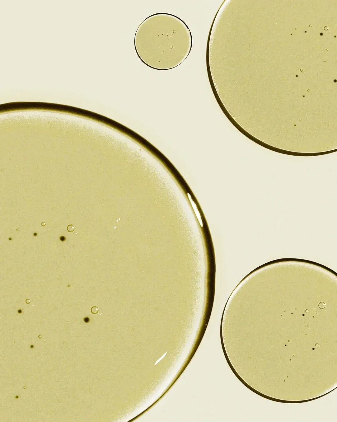Close-up of translucent golden cleansing oil droplets on a light background, highlighting texture and clarity